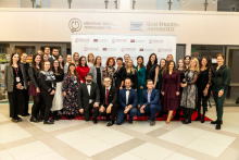 RSU MITC kolēģi MITC jubilejā vienojušies kopbildē, aiz viņiem MITC un RSU logo 